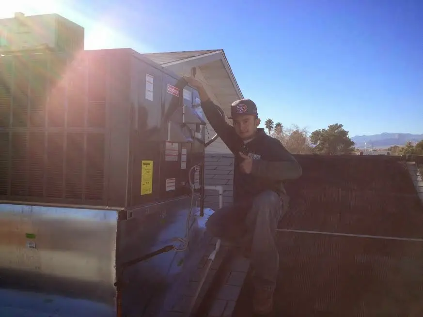 HVAC technician performing AC Tune-Up on a rooftop unit in Washington Terrace